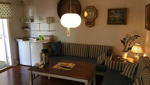 Ein gemütliches Wohnzimmer mit einem gestreiften Sofa, einem Holztisch, einer Uhr und einer Lampe.