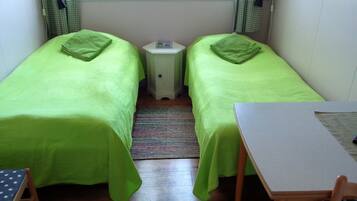 A small room with two single beds, a small table, and a chair.