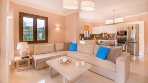 Un salón moderno con un sofá color crema, una mesa de centro y vistas a la cocina.
