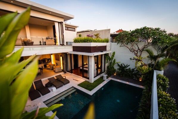A modern house with a pool, outdoor seating, and lush greenery. - Villa Portsea (Seminyak)