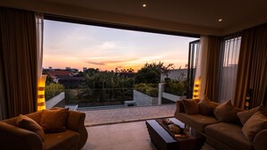En moderne stue med sofaarrangement og sofabord, en balkon med havudsigt og gelænder af glas.