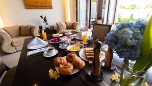 Et morgenbord med croissanter, en skål med frugt og en vase med blomster.