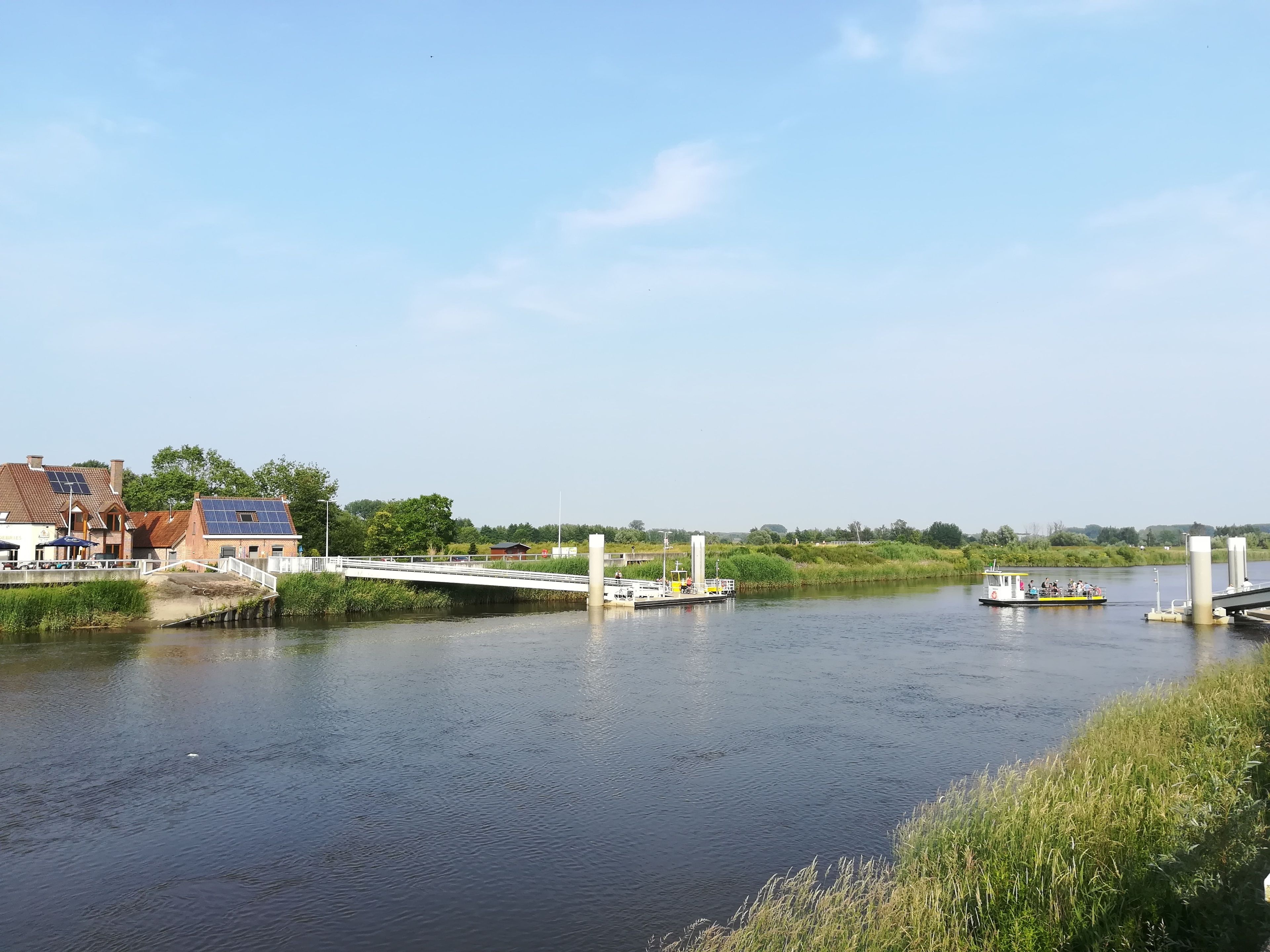 Uitzicht op de rivier met een brug, een boot en gebouwen langs het water.