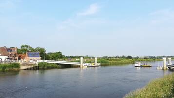 Uitzicht op de rivier met een brug, een boot en gebouwen langs het water.