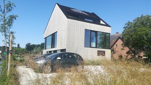 Een modern herenhuis met twee verdiepingen, grote ramen en een schuin dak.