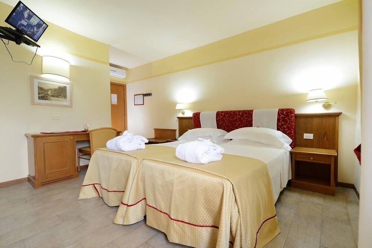 Ein Hotelzimmer mit zwei Betten, einem Schreibtisch und einem Fernseher.