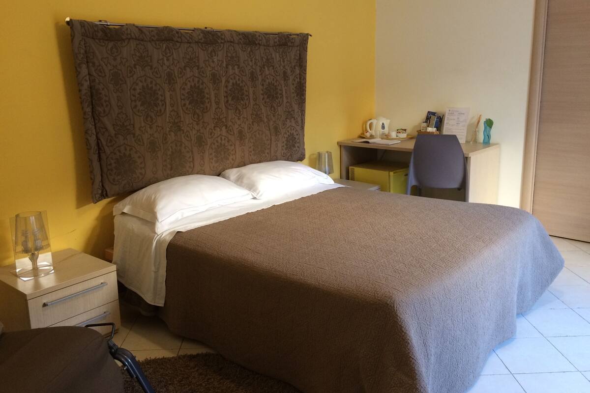 A hotel room with a bed, a desk, and a chair.