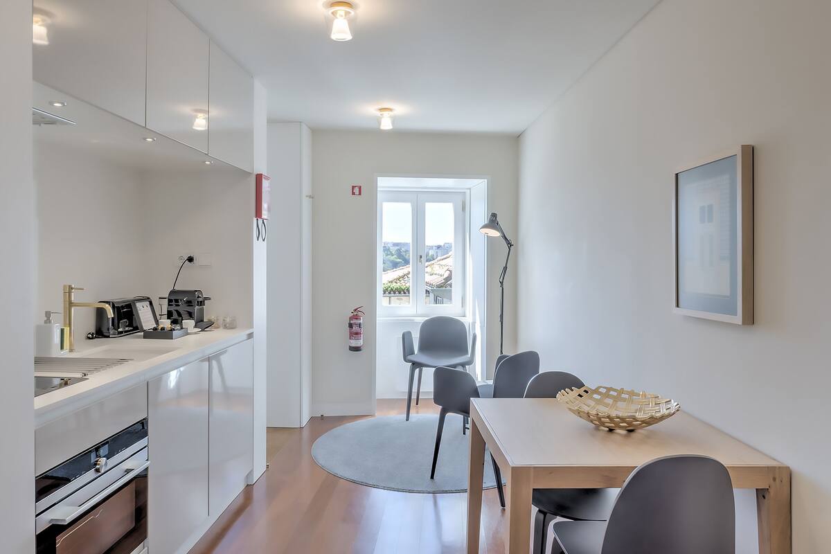 A modern kitchen with a dining area, a coffee machine, and a fire extinguisher.