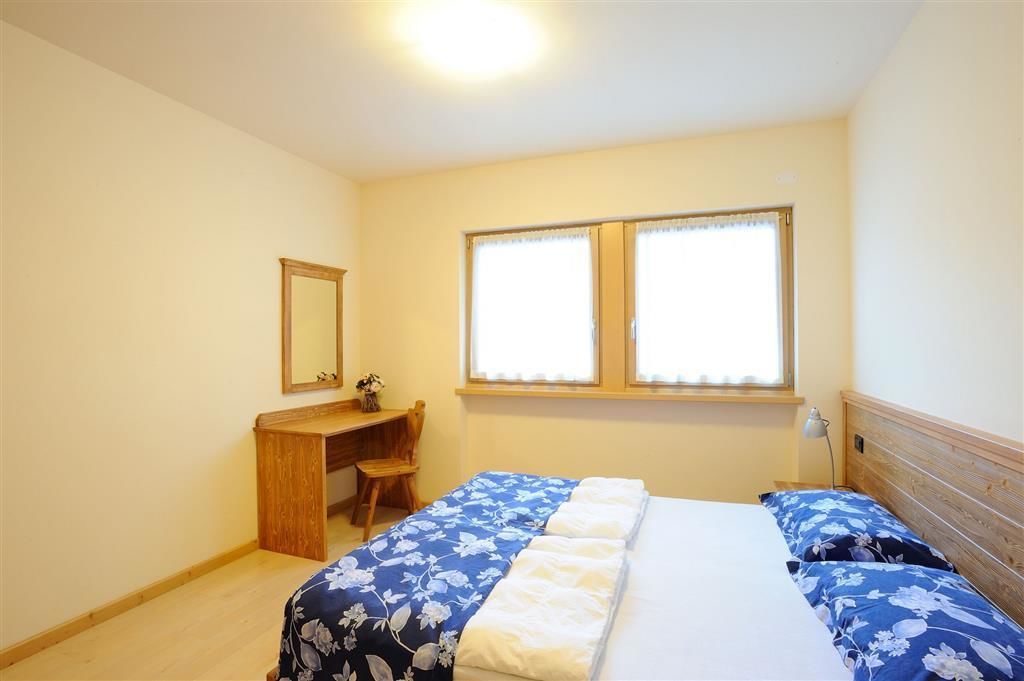 Un dormitorio con cama, escritorio y ventana.