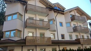 Edifício residencial com vários andares, varandas, telhado plano e fachada uniforme.