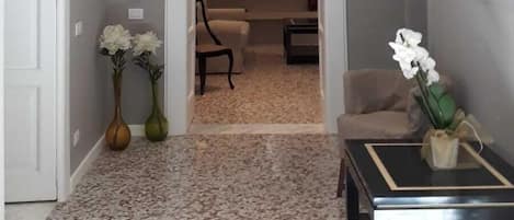 Un pasillo con suelo alfombrado, una puerta a la izquierda y un espejo a la derecha.
