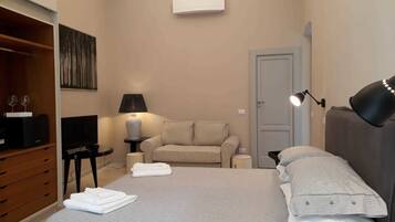 Un dormitorio con cama, sofá, televisor, lámpara y armario.