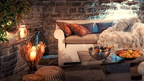 A cozy seating area with a sofa, cushions, a bowl of snacks, a candle holder, and a decorative bowl with a candle.