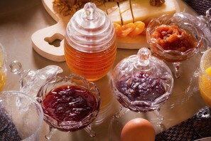 A variety of glass containers with different types of preserves and a honey jar.