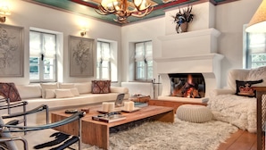 A spacious living room with a fireplace, comfortable seating, and artwork on the walls.