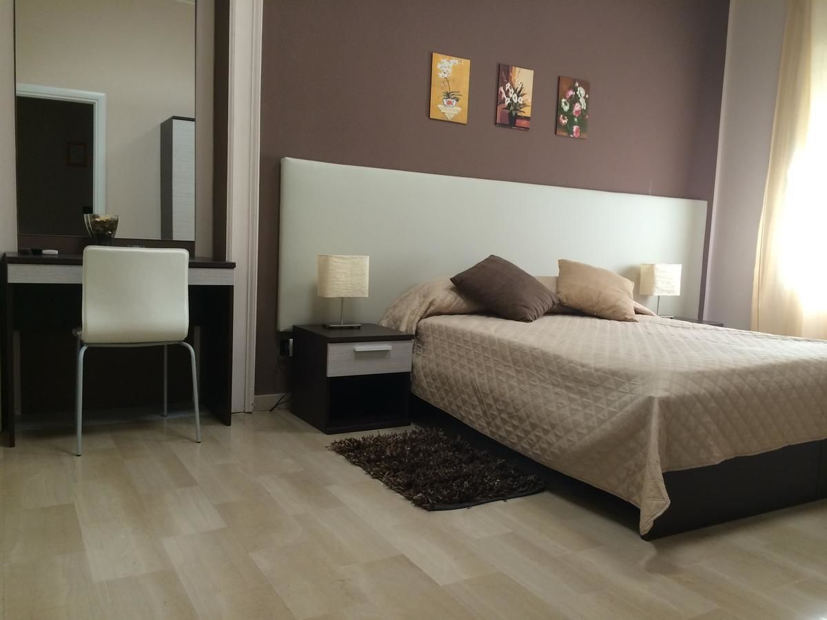 A bedroom with a bed, bedside tables, a desk, and a chair.