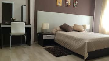 A bedroom with a bed, bedside tables, a desk, and a chair.