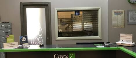A reception desk with a sign reading "Civico 7 Affittacamere."