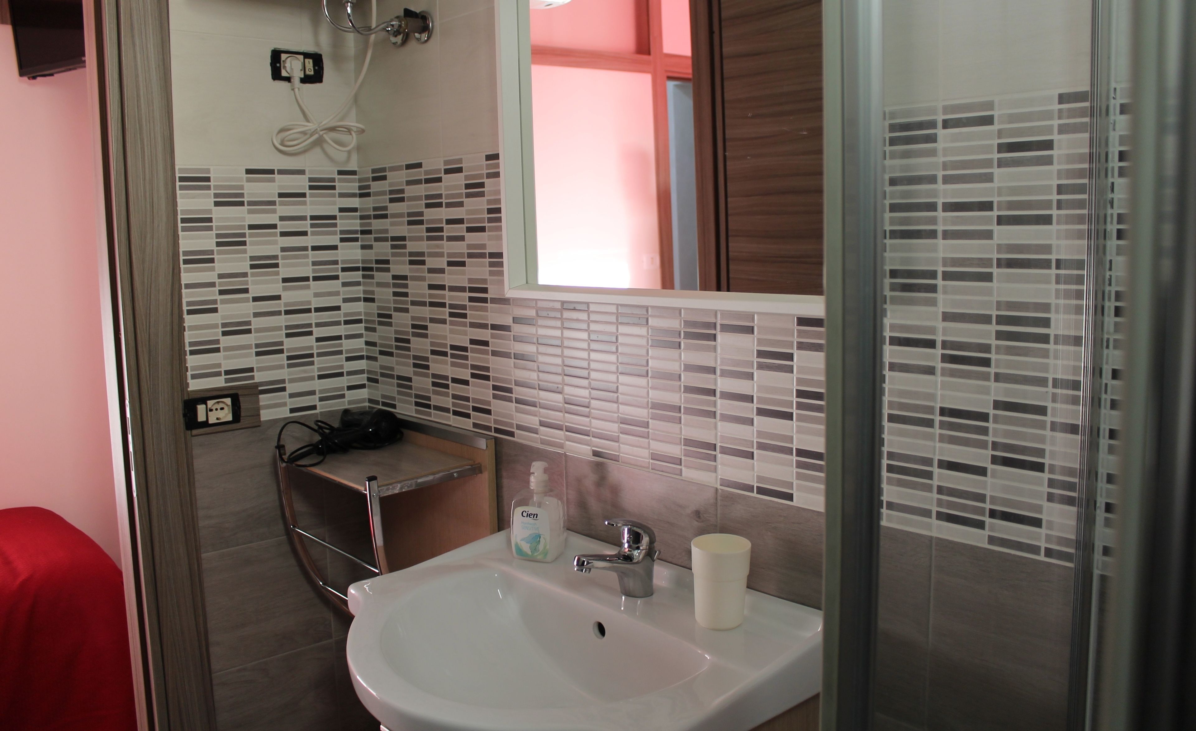 A bathroom with a white sink, a mirror, and a shower area.