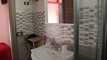 A bathroom with a white sink, a mirror, and a shower area.