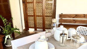 Mesa de jantar posta com louça branca, incluindo pratos, um bule, um açucareiro e um jarro.