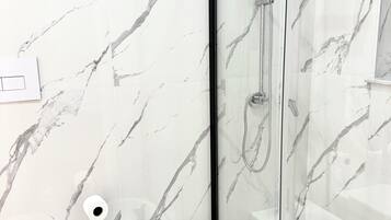 A bathroom with a glass-enclosed shower, a white toilet, and a bidet.
