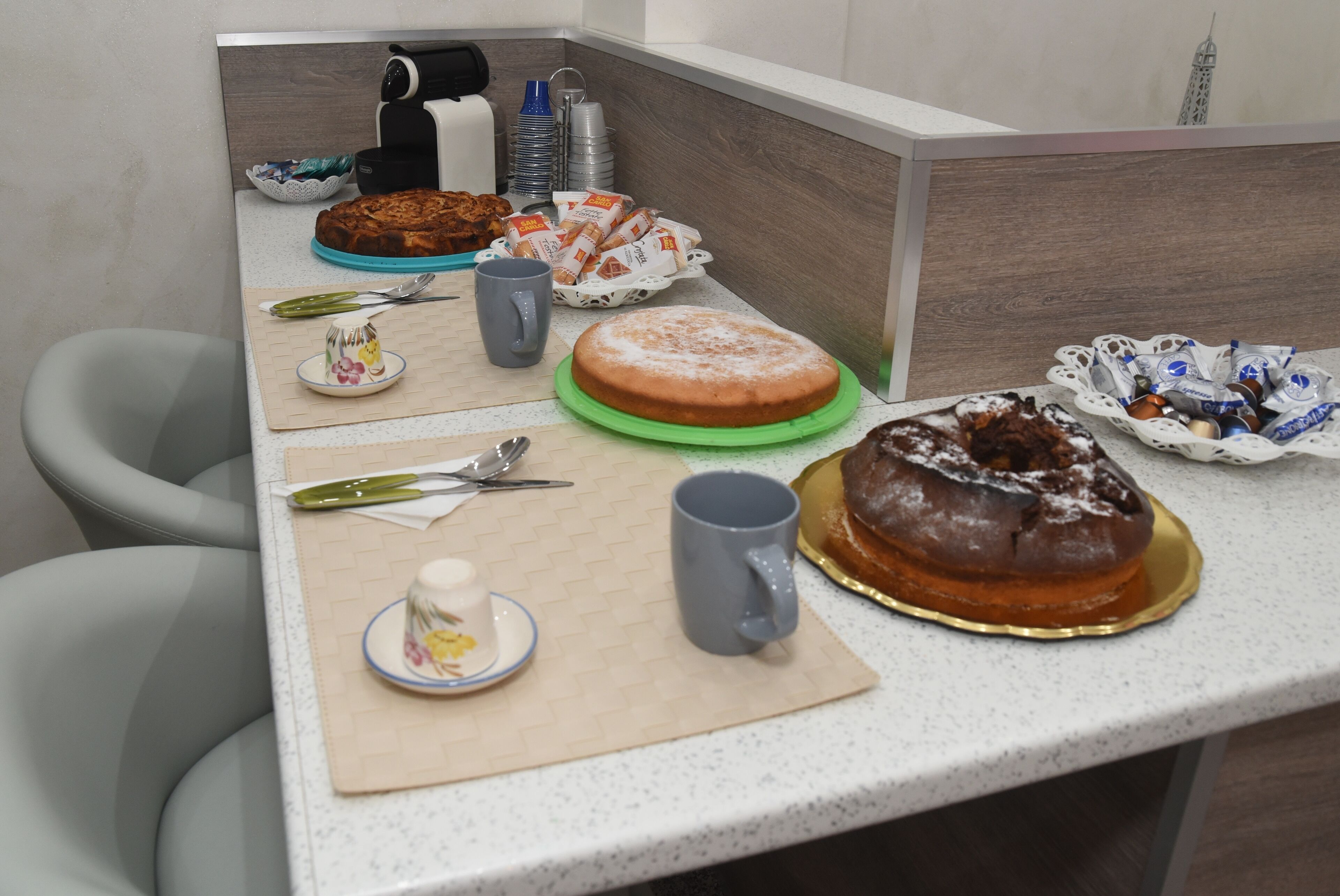 Eine Küchenarbeitsplatte mit verschiedenen Lebensmitteln, darunter Kuchen und Gebäck, sowie eine Kaffeemaschine.