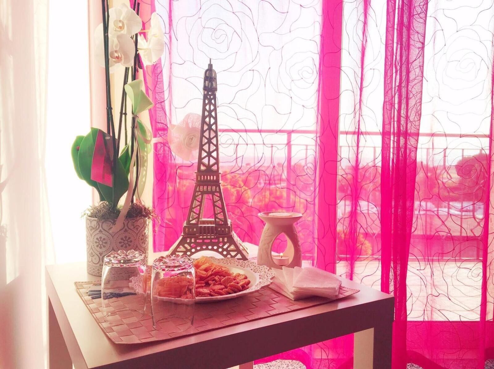 A table with a decorative Eiffel Tower model, a vase with green plants, and a plate of snacks.