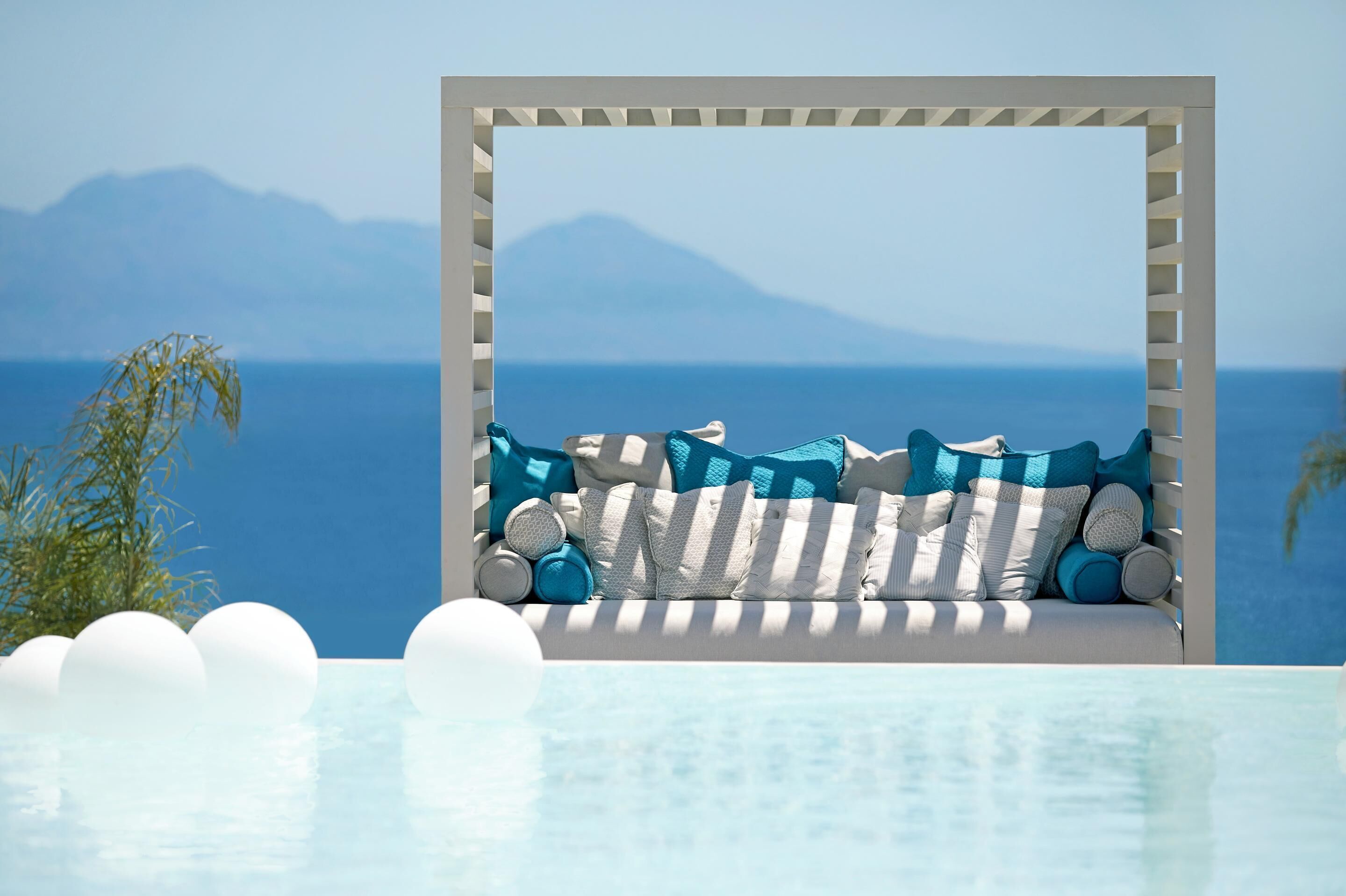 Zona relax a bordo piscina con vista sul mare e sulle montagne.