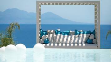Zona relax a bordo piscina con vista sul mare e sulle montagne.