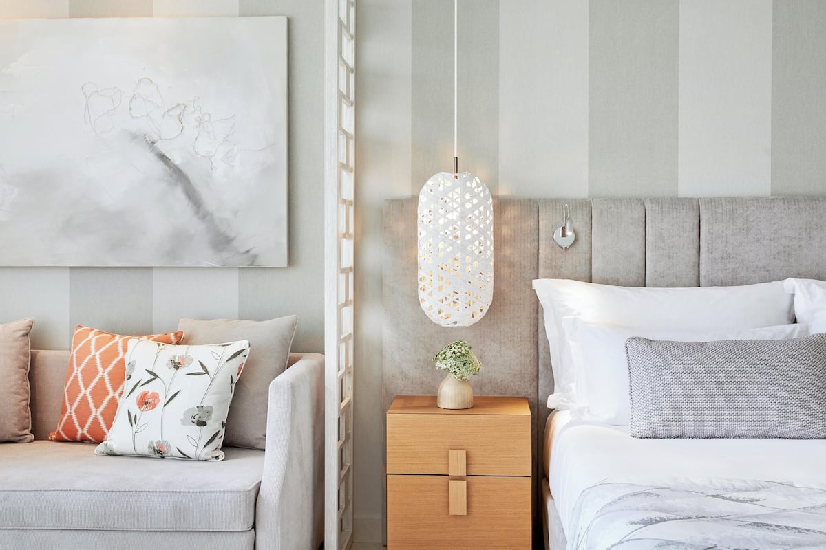 A modern bedroom with a bed, nightstand, and a hanging light fixture.