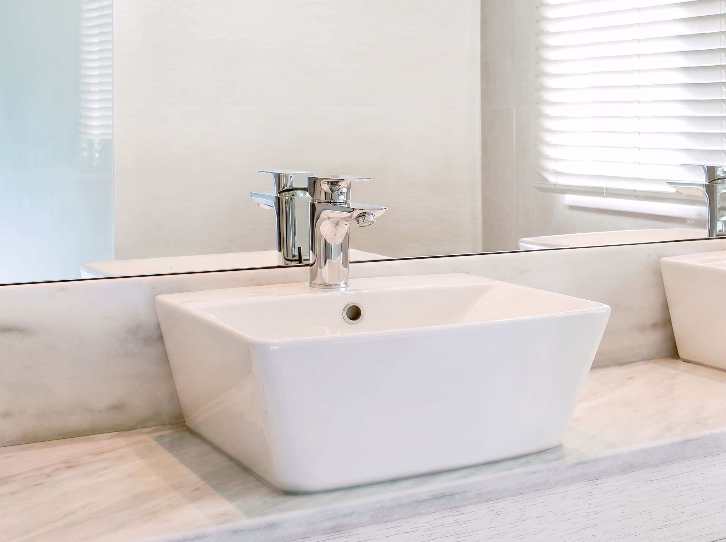 A bathroom with a white sink, chrome faucet, and a mirror above it.