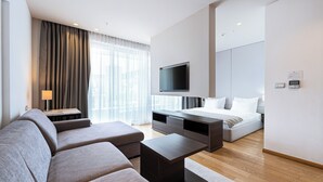 A modern hotel room with a sofa, a TV, a bed, and a desk. - Hotel Wow (Budva)