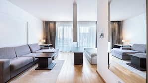 A modern living room with a sectional sofa, a coffee table, and a TV stand. - Hotel Wow (Budva)