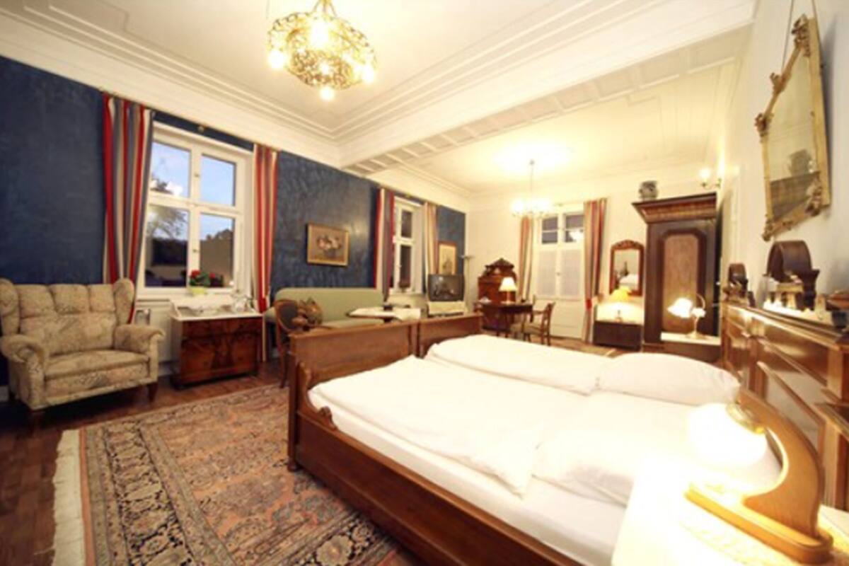 A traditional room with a large bed, a wooden dresser, a chair, and a desk.