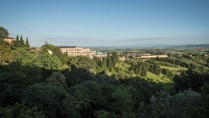 A view of a building surrounded by lush greenery and distant hills. - B&B Paolina (Siena)