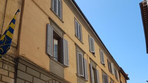 A building with a wooden door and multiple windows with shutters. - B&B Paolina (Siena)