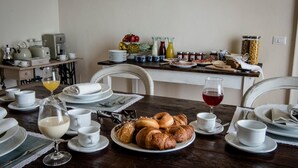 A breakfast table set with croissants, fruit, and beverages, with a coffee maker and tea set in the background. - B&B Paolina (Siena)