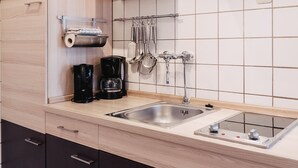 Una cucina moderna con lavello in acciaio inossidabile, macchina da caffè e utensili pensili.