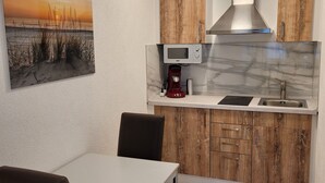 Una cucina compatta con mobili in legno, un forno a microonde, una macchina da caffè e un lavandino.