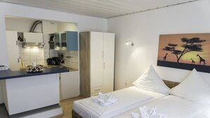 Una camera d'albergo con un letto, angolo cottura e un quadro con giraffe.