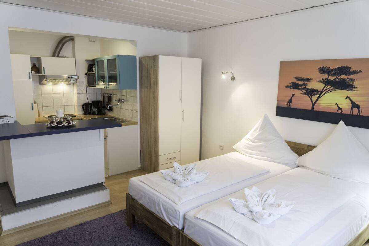 Habitación de hotel con cama, kitchenette pequeña y un cuadro de jirafas en la pared.