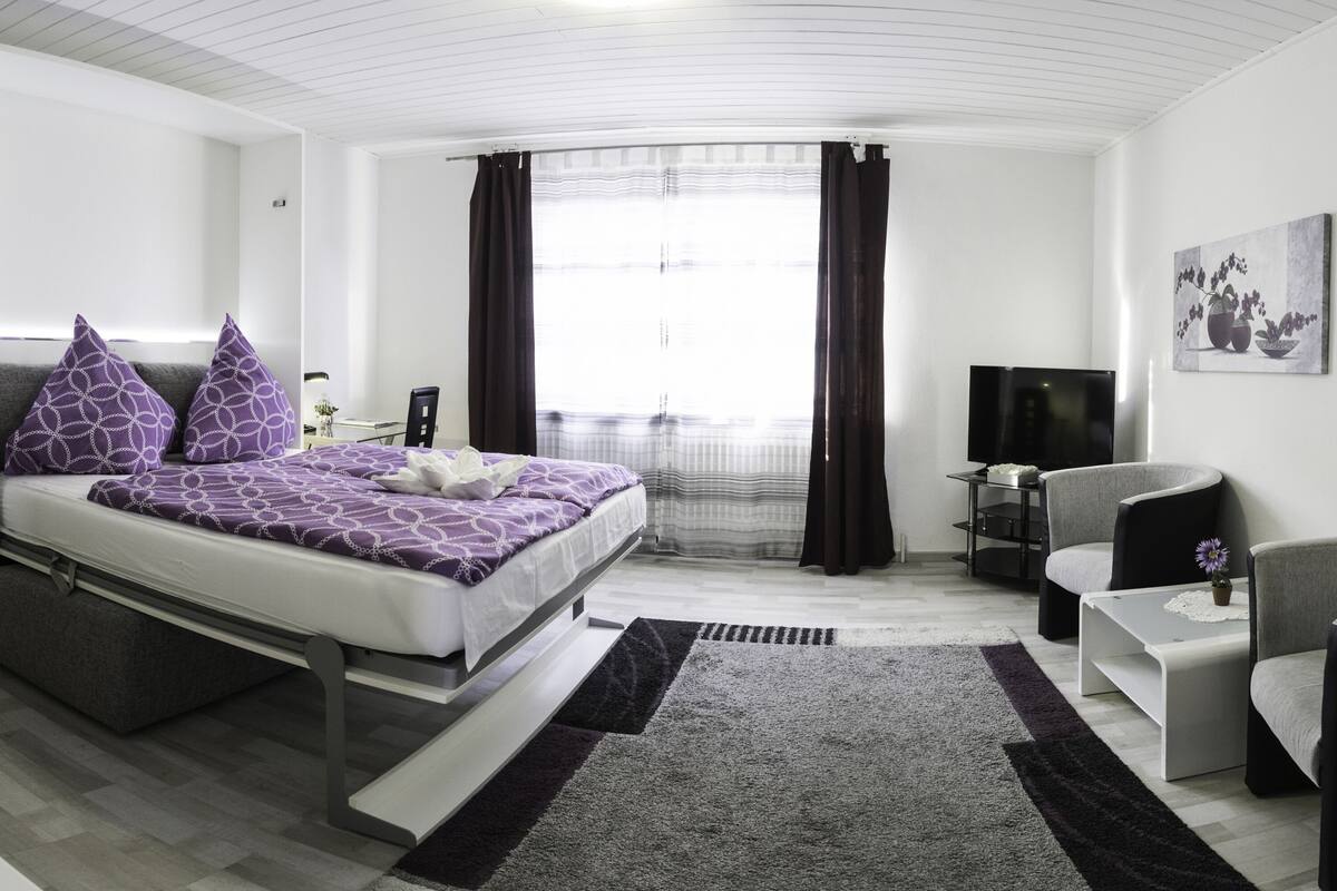 Una habitación de hotel moderna con cama, televisor, escritorio y silla.