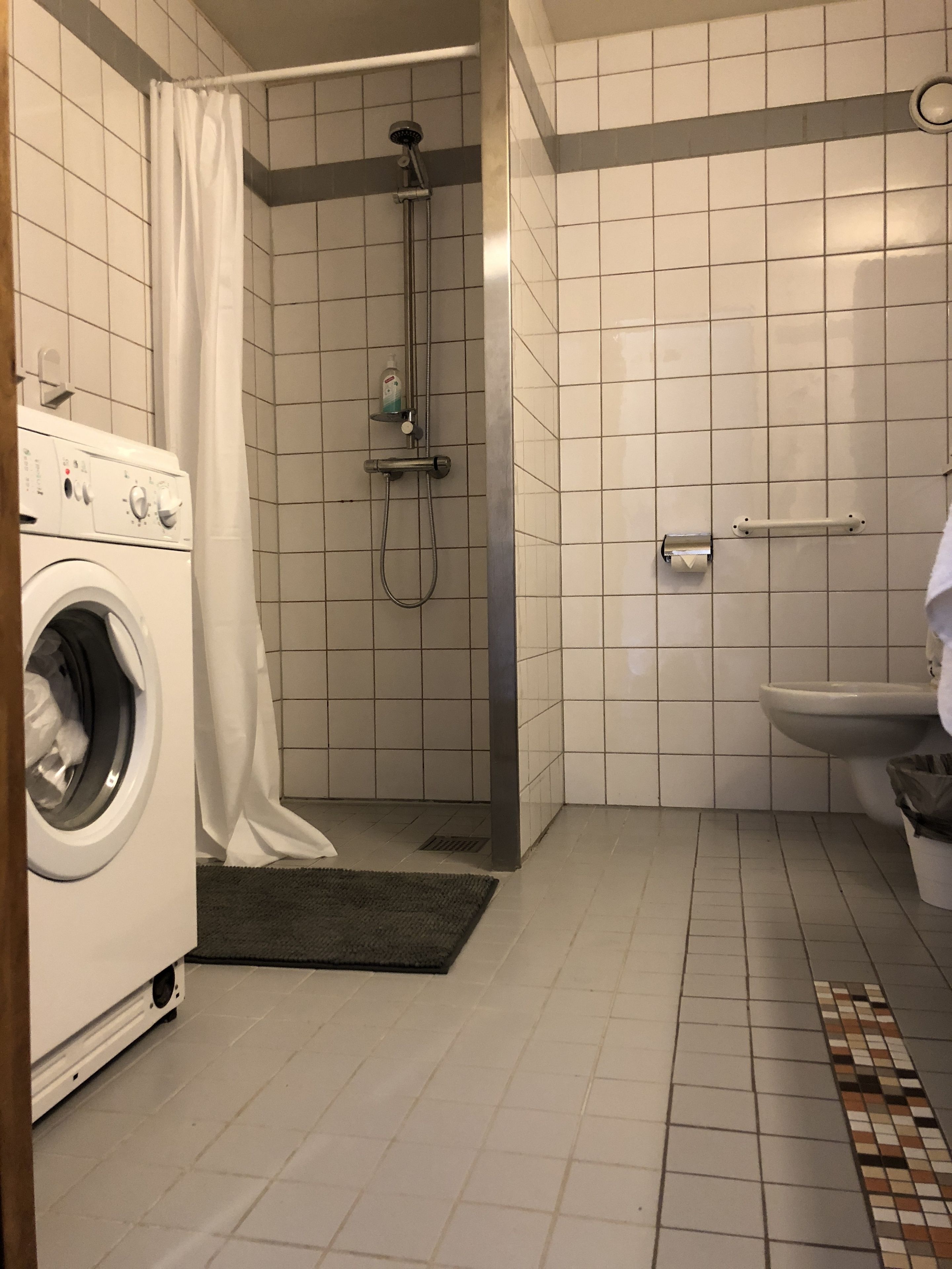 Un bagno compatto con lavatrice, doccia e WC.