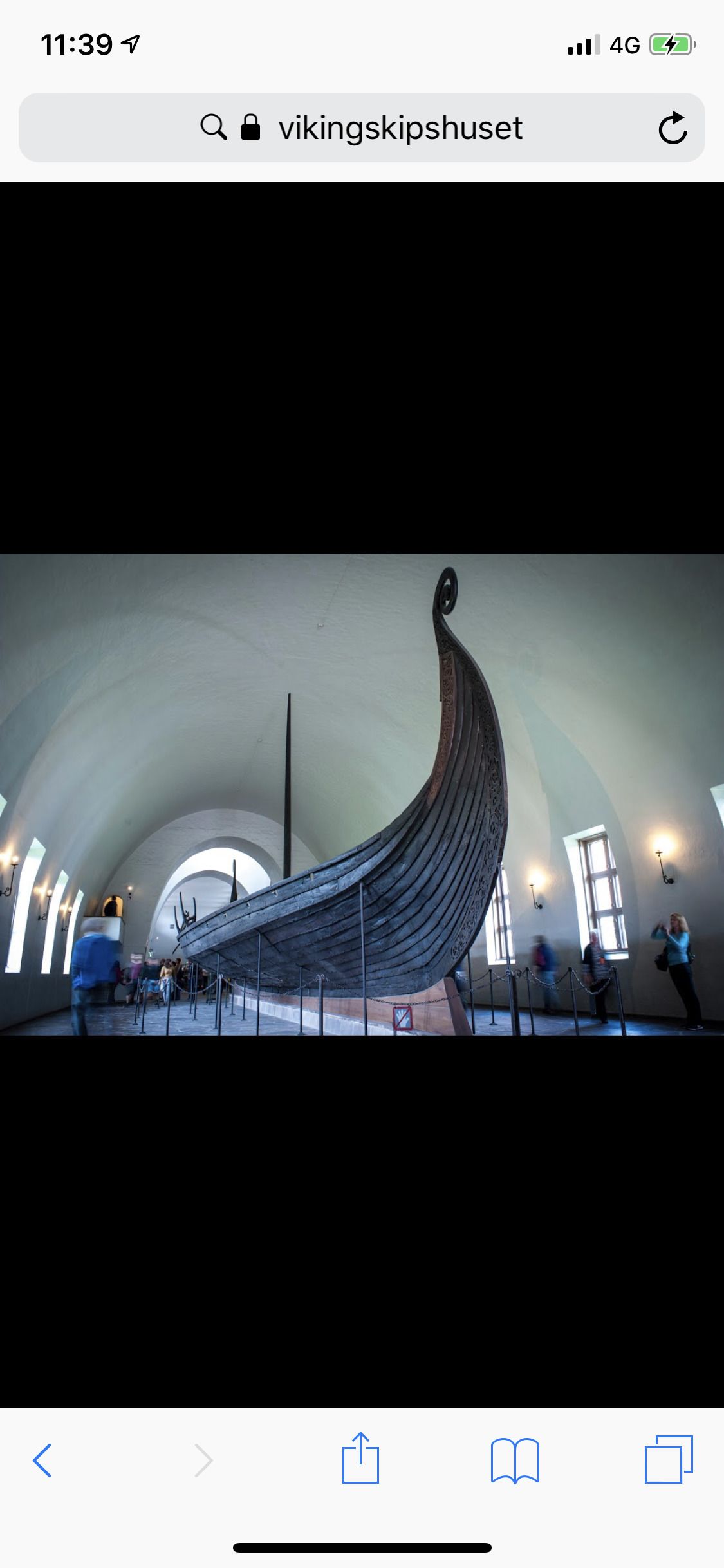 Een groot Vikingschip-expositie in een museum met een hoge gewelfde plafond en natuurlijk licht dat door ramen naar binnen schijnt.