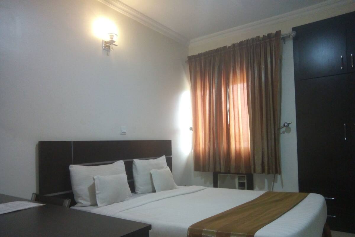 A hotel room with a bed, a desk, and a wardrobe.