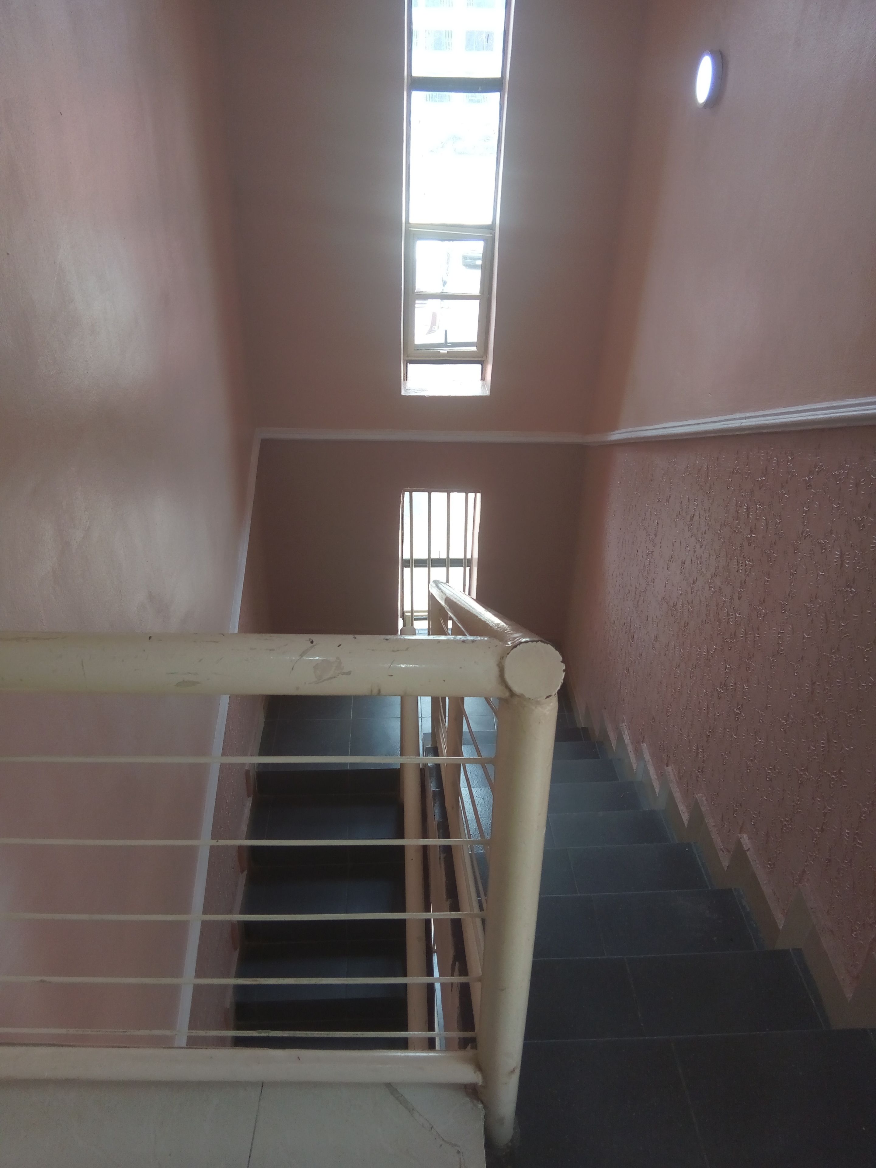 A staircase with a handrail, a window, and a wall with a textured pattern.