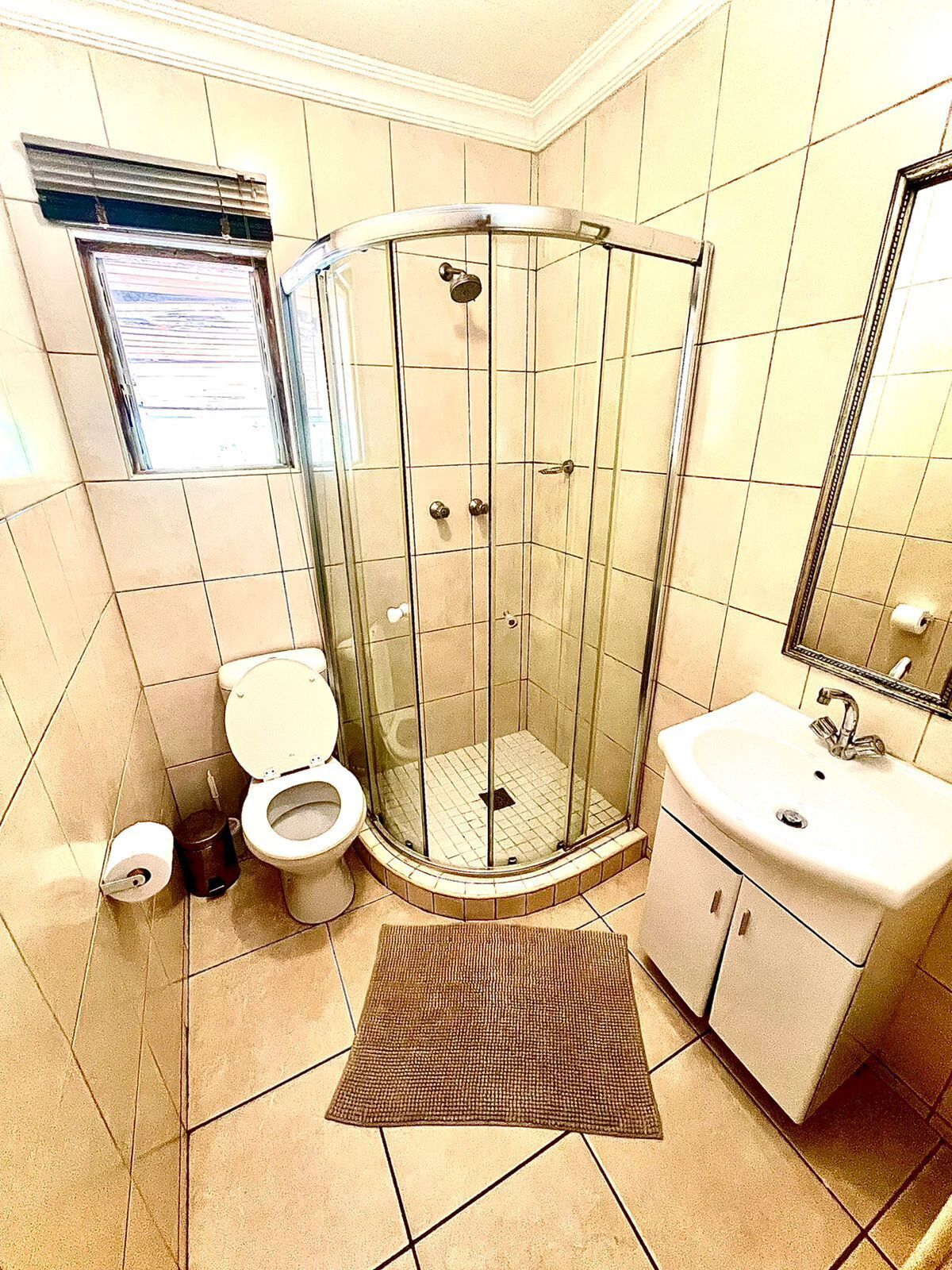 Une salle de bain avec une douche à parois de verre, des toilettes, un lavabo et un miroir.
