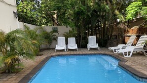 A swimming pool with white lounge chairs and a sign indicating pool hours. - St Lucia Palms (St. Lucia)