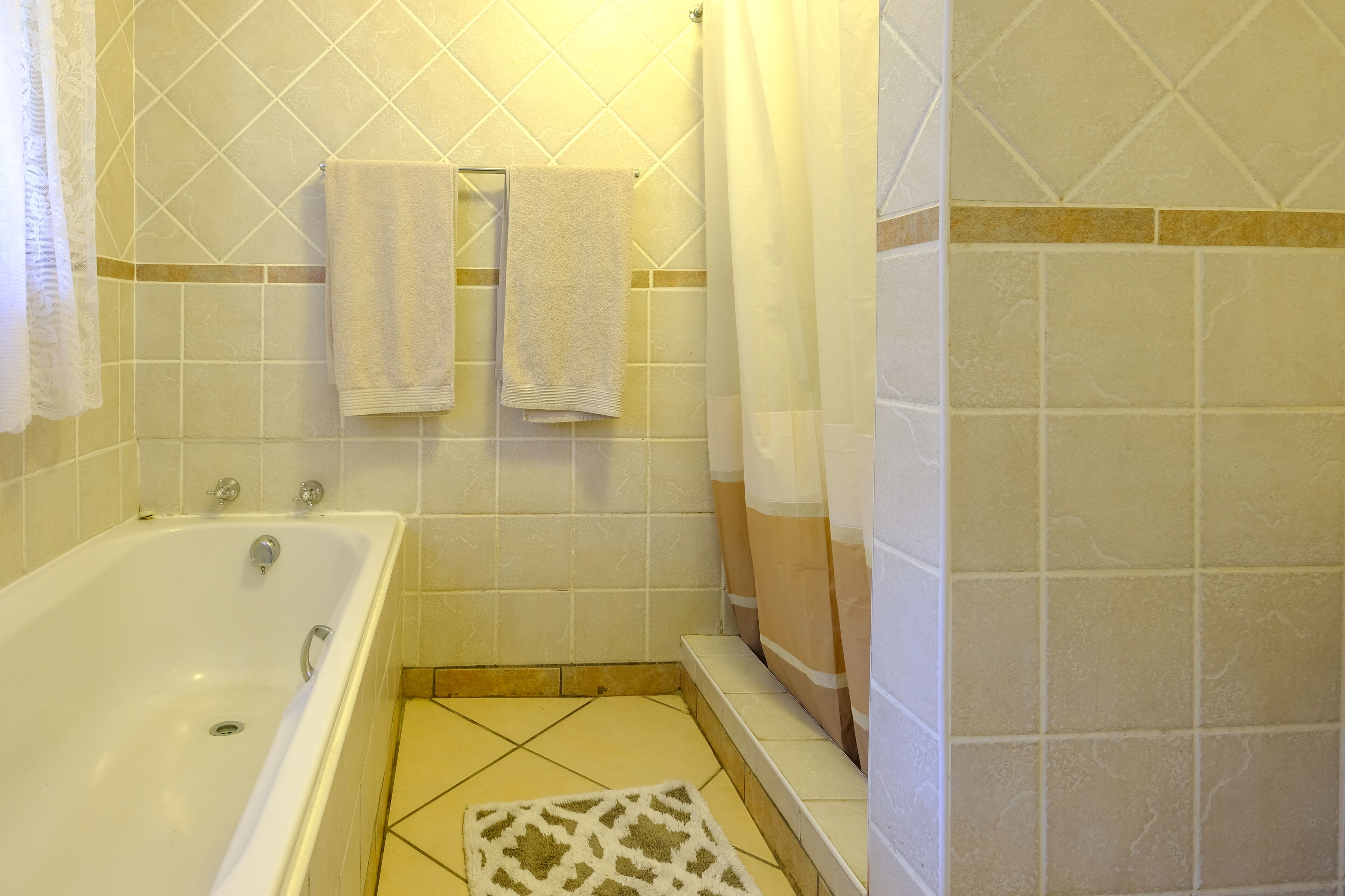 Un baño con bañera, dos toallas colgadas en la pared y una cortina de ducha.